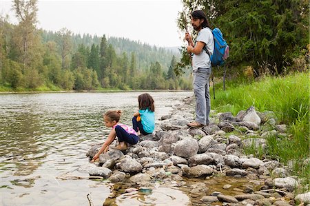 female hiker crouching - Father and daughters hiking, resting at lakeside Stock Photo - Premium Royalty-Free, Code: 6113-09111957