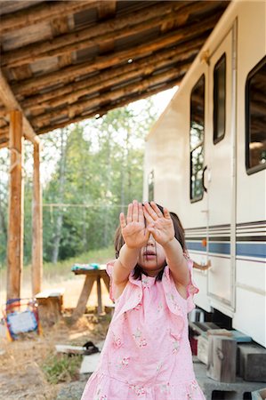 Portrait shy girl hiding face with hands outside rural camper Stock Photo - Premium Royalty-Free, Code: 6113-09111959