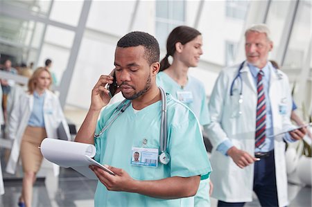 Male nurse with clipboard talking on cell phone in hospital corridor Foto de stock - Sin royalties Premium, Código: 6113-09111910