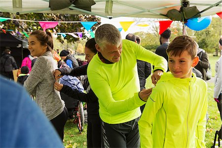 Father pinning marathon bib on son at charity run in park tent Stock Photo - Premium Royalty-Free, Code: 6113-09131275