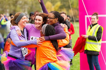 funny ethnic pictures - Enthusiastic female runners in tutus hugging at finish line, celebrating Stock Photo - Premium Royalty-Free, Code: 6113-09131221