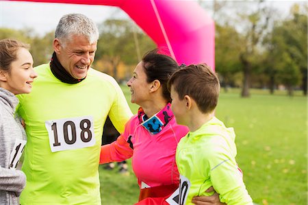 Happy family hugging at charity run in park Stock Photo - Premium Royalty-Free, Code: 6113-09131341