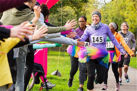 start finish run - Enthusiastic female runners in tutus high-fiving spectators at charity run in park Stock Photo - Premium Royalty-Free, Code: 6113-09131375