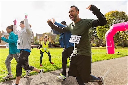 Exuberant male runner cheering at charity run in sunny park Foto de stock - Sin royalties Premium, Código: 6113-09131392