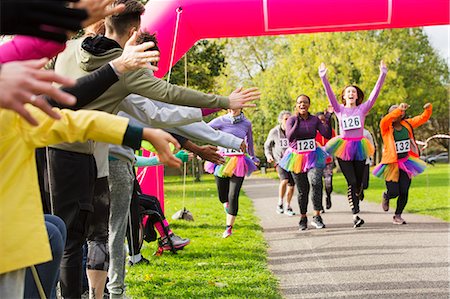 runner crossing finish line - Enthusiastic female runners in tutus nearing finish line at charity run in park Stock Photo - Premium Royalty-Free, Code: 6113-09131430