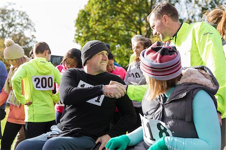 simsearch:6113-07565319,k - Runner shaking hands with man in wheelchair at charity race in sunny park Stock Photo - Premium Royalty-Free, Code: 6113-09131435