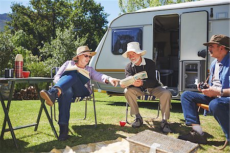 Active senior friends reading outside camper van at sunny summer campsite Fotografie stock - Premium Royalty-Free, Codice: 6113-09131514