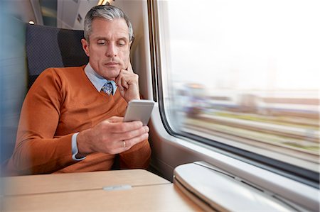 reading (from a meter or gauge) - Focused businessman using smart phone at passenger train window Stock Photo - Premium Royalty-Free, Code: 6113-09131652