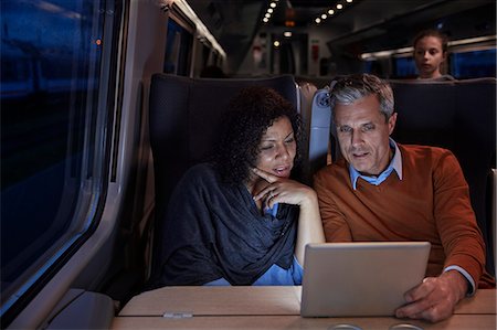 Couple using digital tablet on dark passenger train at night Stock Photo - Premium Royalty-Free, Code: 6113-09131661
