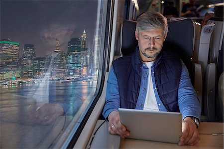 Man using digital tablet on passenger train at night Stock Photo - Premium Royalty-Free, Code: 6113-09131601