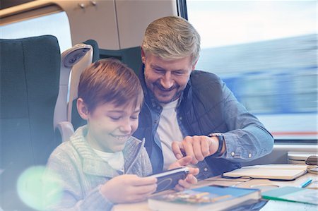 Father and son using smart phone on passenger train Stock Photo - Premium Royalty-Free, Code: 6113-09131602