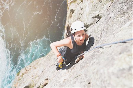 Focused, determined female rock climber scaling rock above sunny ocean Stock Photo - Premium Royalty-Free, Code: 6113-09131779