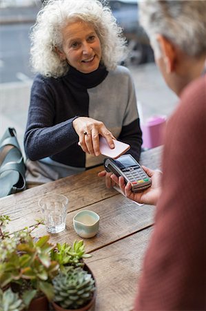 reaching senior - Woman using smart phone contactless payment at cafe Stock Photo - Premium Royalty-Free, Code: 6113-09131708