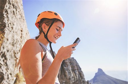 Smiling female rock climber using smart phone Stock Photo - Premium Royalty-Free, Code: 6113-09131731