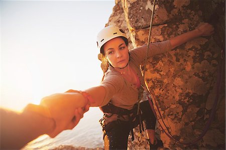 Focused female rock climber reaching for arm Stock Photo - Premium Royalty-Free, Code: 6113-09131734