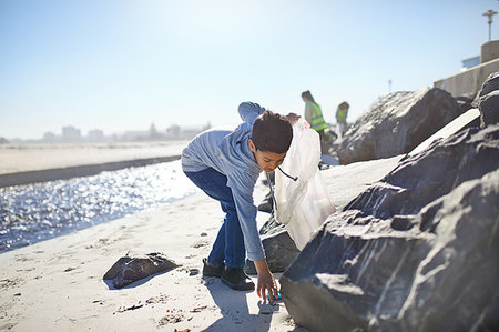 simsearch:685-02941312,k - Boy volunteer picking up litter on sunny beach Photographie de stock - Premium Libres de Droits, Code: 6113-09240182