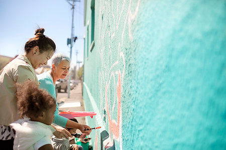 simsearch:6113-09240262,k - Female volunteers painting mural on sunny wall Foto de stock - Royalty Free Premium, Número: 6113-09240251