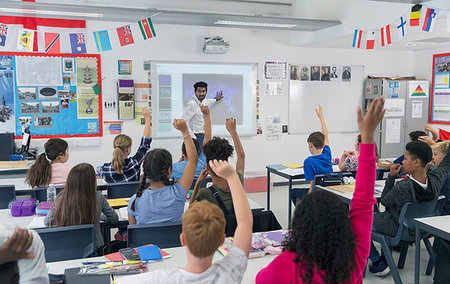 Male teacher leading lesson at projection screen in classroom with students raising hands Stock Photo - Premium Royalty-Free, Code: 6113-09240384