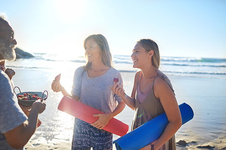 Mother and daughter with yoga mats eating fresh berries on sunny beach during yoga retreat Stock Photo - Premium Royalty-Free, Code: 6113-09240495