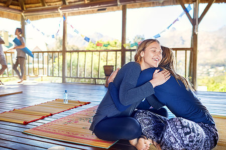 Happy mother and daughter hugging on yoga mats in hut during yoga retreat Stock Photo - Premium Royalty-Free, Code: 6113-09240551
