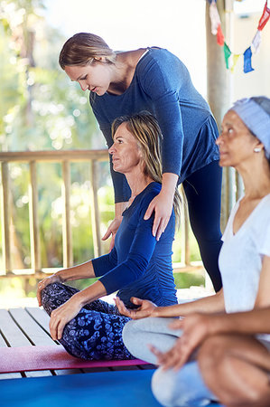 Female instructor adjusting student's shoulders during yoga retreat Stock Photo - Premium Royalty-Free, Code: 6113-09240591