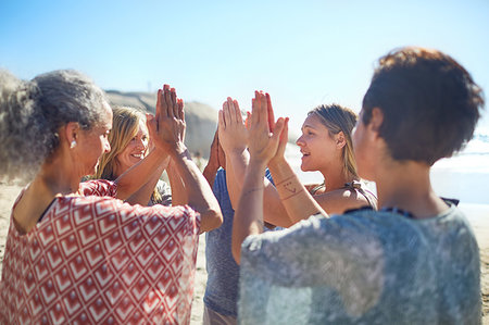 Group standing in circle with hands clasped on sunny beach during yoga retreat Stock Photo - Premium Royalty-Free, Code: 6113-09240592