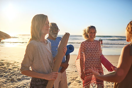 Smiling friends with yoga mats on sunny beach during yoga retreat Stock Photo - Premium Royalty-Free, Code: 6113-09240530