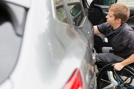 Young woman in wheelchair opening car door Stock Photo - Premium Royalty-Free, Code: 6113-09240687