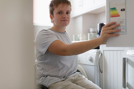 Portrait confidant young woman in wheelchair in apartment kitchen Stock Photo - Premium Royalty-Free, Code: 6113-09240617