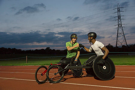 Paraplegic athletes fist bumping on sports track, training for wheelchair race at night Stock Photo - Premium Royalty-Free, Code: 6113-09240748
