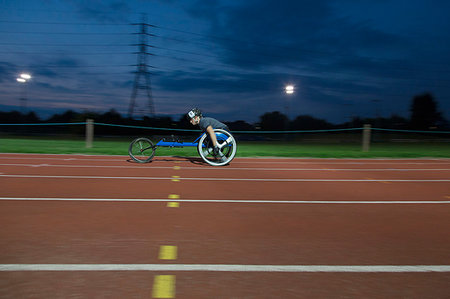simsearch:6113-09240745,k - Young female paraplegic athlete speeding along sports track in wheelchair race at night Stock Photo - Premium Royalty-Free, Code: 6113-09240732
