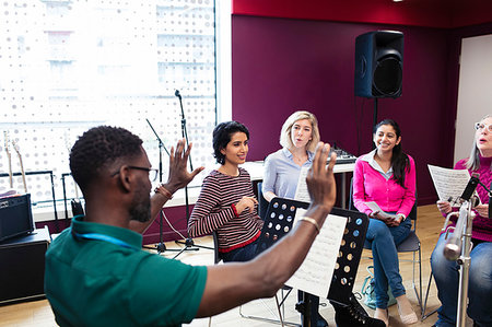 simsearch:6113-09168289,k - Male conductor leading women singing in music recording studio Stock Photo - Premium Royalty-Free, Code: 6113-09240862