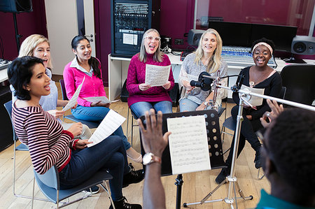 simsearch:6113-09168289,k - Male conductor leading womens choir with sheet music singing in music recording studio Stock Photo - Premium Royalty-Free, Code: 6113-09240889