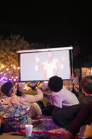 Friends watching movie on projection screen in backyard Photographie de stock - Premium Libres de Droits, Code: 6113-09241379