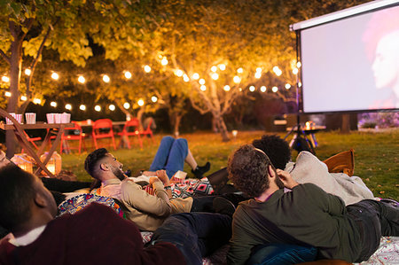 eating at night - Friends relaxing, watching movie on projection screen in backyard Stock Photo - Premium Royalty-Free, Code: 6113-09241338