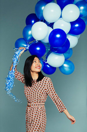 simsearch:633-01992711,k - Smiling, carefree woman with blue and white balloon bunch Stock Photo - Premium Royalty-Free, Code: 6113-09272464