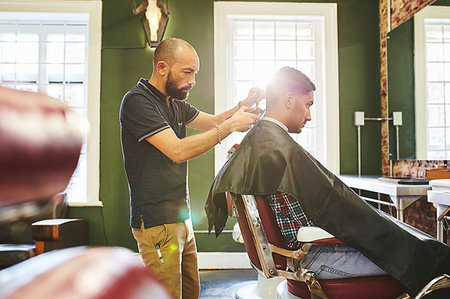 simsearch:6113-08521588,k - Focused male barber giving customer a haircut in barbershop Foto de stock - Sin royalties Premium, Código: 6113-09272565