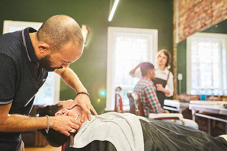 Male barber shaving face of customer in barbershop Stock Photo - Premium Royalty-Free, Code: 6113-09272585