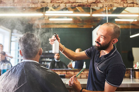 Male barber spraying hair of customer in barbershop Stock Photo - Premium Royalty-Free, Code: 6113-09272589