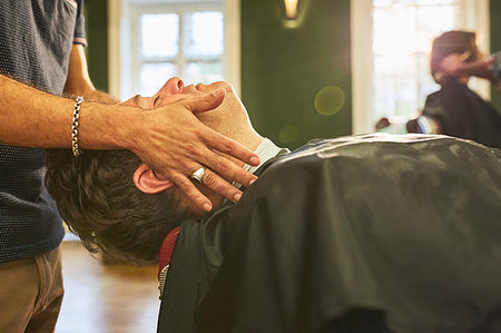 Male barber massaging face of customer in barbershop Stock Photo - Premium Royalty-Free, Code: 6113-09272594