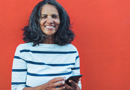 simsearch:614-08031039,k - Portrait smiling, confident woman using smart phone against red background Stock Photo - Premium Royalty-Free, Code: 6113-09272697