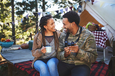 simsearch:6113-08947425,k - Affectionate young couple with binoculars drinking coffee at campsite Stock Photo - Premium Royalty-Free, Code: 6113-09272772