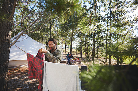 Man hanging laundry on clothesline at campsite in woods Stock Photo - Premium Royalty-Free, Code: 6113-09272798