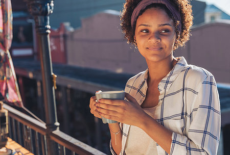 simsearch:6113-08321133,k - Smiling young woman drinking coffee on sunny balcony Stock Photo - Premium Royalty-Free, Code: 6113-09272729