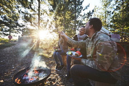 simsearch:832-08007476,k - Happy friends eating at sunny campsite in woods Stock Photo - Premium Royalty-Free, Code: 6113-09272806