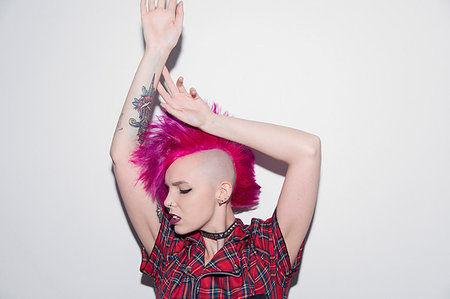 Portrait confident young woman with pink mohawk dancing Stock Photo - Premium Royalty-Free, Code: 6113-09220508