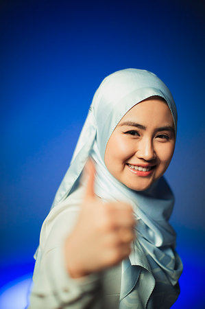 Portrait smiling, confident young woman in blue silk hijab gesturing thumbs-up Stock Photo - Premium Royalty-Free, Code: 6113-09220514