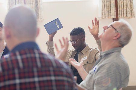 simsearch:6113-09220799,k - Men with bible praying with arms raised in prayer group Fotografie stock - Premium Royalty-Free, Codice: 6113-09220808