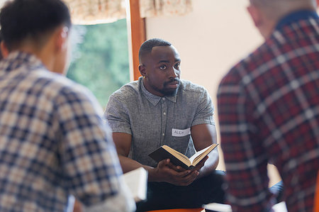 Attentive young man with bible in prayer group Stock Photo - Premium Royalty-Free, Code: 6113-09220813