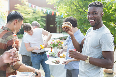 Portrait smiling young man enjoying barbecue with friends Stock Photo - Premium Royalty-Free, Code: 6113-09239752